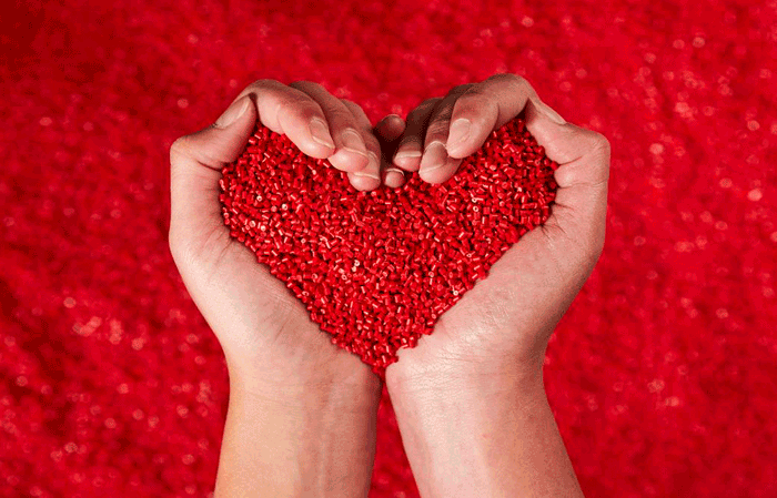 Woman hands, heart shaped holding red granulates