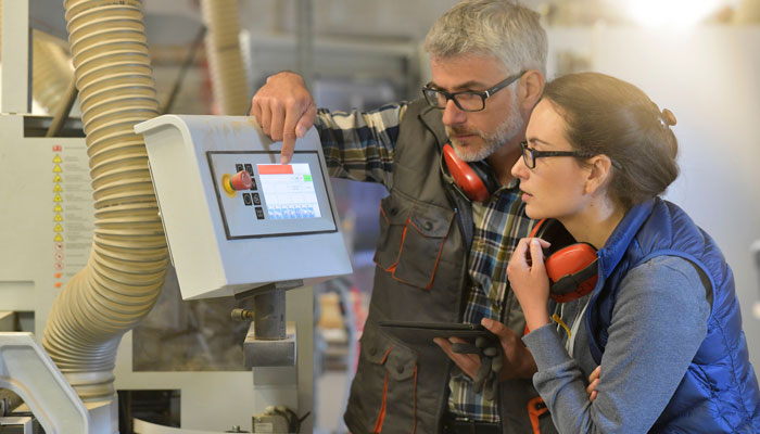 Employees in production looking on a digital screen
