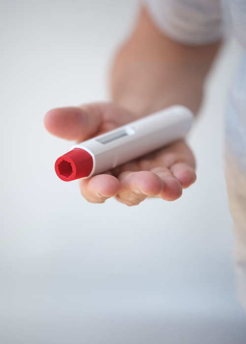 A hand holding a drug delivery device