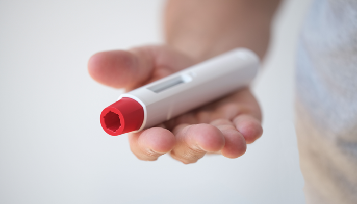 Hand holding drug delivery device.