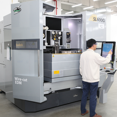 Nolato Dongguan employee standing in front of a machine.