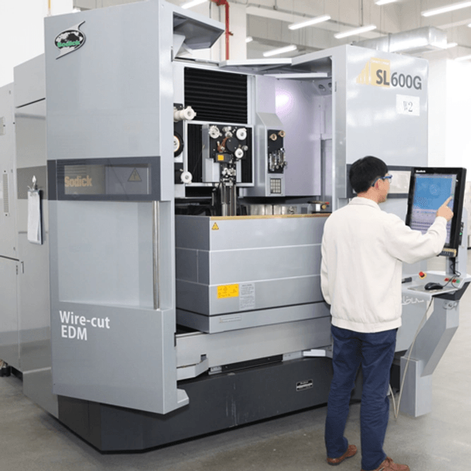 Nolato Dongguan employee standing in front of a machine.